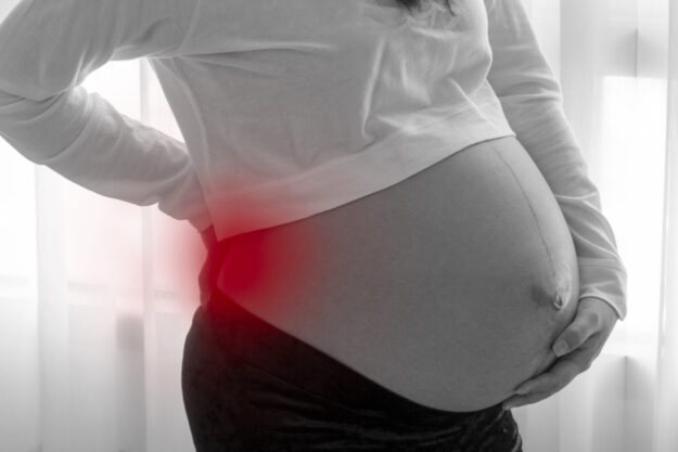 pregnant women having back ache from weight of baby before birth black and white