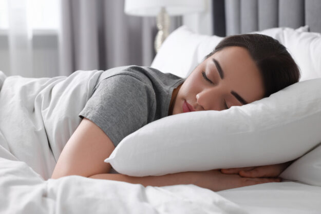 Beautiful young woman sleeping in soft bed at home